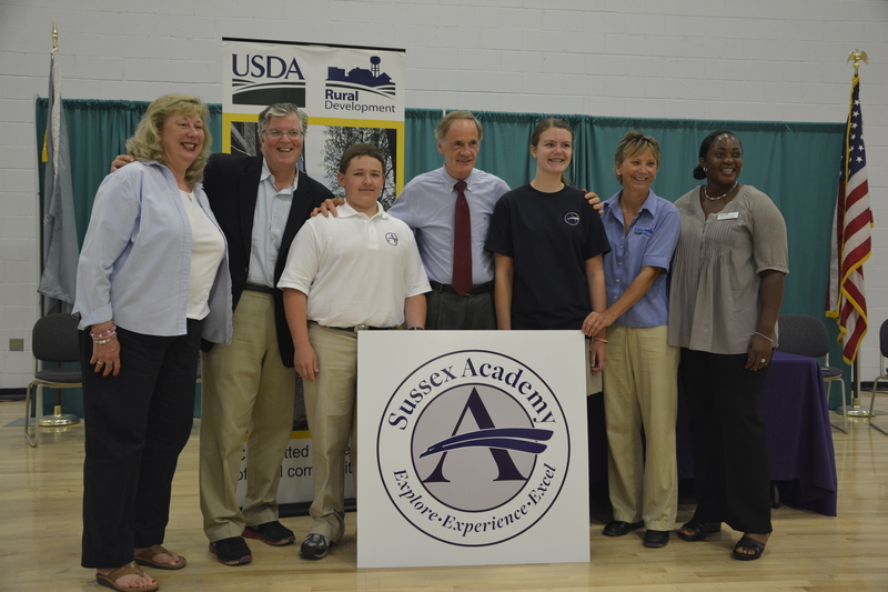During a tour of the new home of Sussex Academy (l-r) USDA Business and Community Director Denise Macleish, USDA Director of Legislative and Public Affairs David Sandretti, rising freshman Cohen Davis, Sen. Tom Carper, rising eighth grader Elise Conlin, Delaware and Maryland Acting State Director Kathy Beisner and USDA representative Angela Tilghman stand with Sussex Academy's new logo. PHOTOS BY LEXI COON