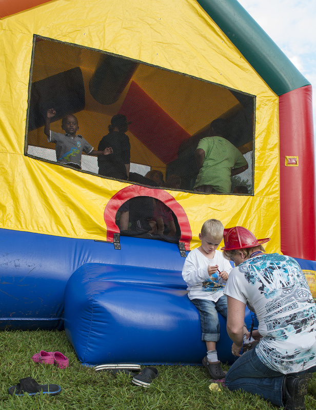 Robert, 4, gets his shoes replaced by his mother Danielle Evans after his stint in the Bouncey House. BY DENY HOWETH