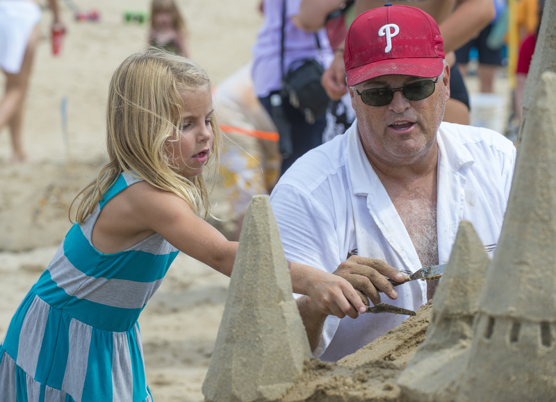 Sophia Hall, 6, lends a hand to Darrell O'Connor on the Community Sandcastle. He provided tips on making a realistic castle as well as structural concepts. BY DENY HOWETH