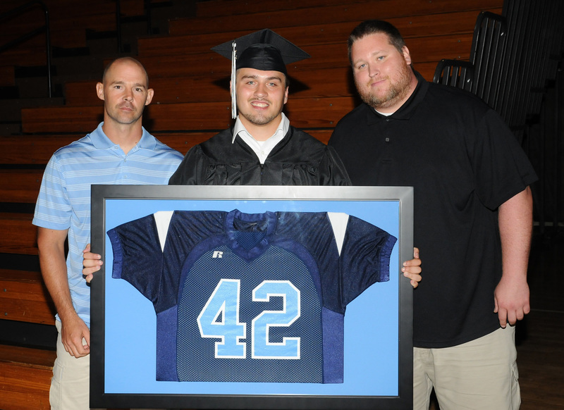 William Krouse II, center, one of the student speakers at the graduation ceremony of James H. Groves Adult High School, receives his framed Lake Forest High School football jersey from his former high school coaches, Jeremy Seilheimer, left, and Jeremey Robinson. Krouse also received the Principal’s Scholarship. SOURCE SUBMITTED