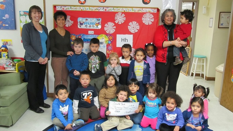 County Bank's Georgetown Branch Manager Janine Ezel, left, visits children and teachers at Primeros Pasos to support the building of a new facility in Georgetown. Primeros Pasos teachers Laura Eaton, standing next to Ezel, and Maria Joseph gather with students for the check presentation. SOURCE SUBMITTED