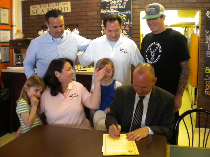 Gov. Markell signs Senate Bill 167, allowing the sale of Blotto Gelato ice cream while (l-r) Sen. Ernie Lopez, R-Lewes; Ron Belfont, co-owner Blotto Gelato; Mike Clampitt, owner Po' Boys Creole and Fresh Catch; Sophia Belfont, Kathleen Belfont, co-owner Blotto Gelato; and Kayla Belfont watch. BY TAGGART HOUCK