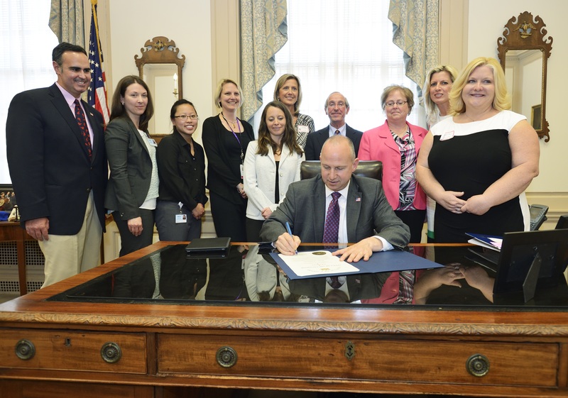 On Tuesday, May 6, Delaware Gov. Jack Markell, seated, signed a tribute honoring Beebe Healthcare as the first medical center in Delaware to receive the Baby-Friendly designation. Shown are (left to right) Sen. Ernie Lopez (R-Lewes), Mollie Poland, Nemours Health and Prevention Services; Marisa Cheng, intern with Nemours; Lisl Phelps, MSN, RN, Delaware Health and Social Services; Kate DuPont Phillips, MPH, CHES, PAPHS, Nemours; Beebe Executive Director of Women’s Health Services Bridget Buckaloo; Beebe Healthcare Board Member David A. Herbert; Beebe Women’s Health Nurse Manager Denice Powell, RN; Beebe Women’s Health Nurse Joan Gay, RN; and Beebe Women’s Health Lactation Specialist Nancy Hastings, RN, IBCLC. BY SCOTT NATHAN