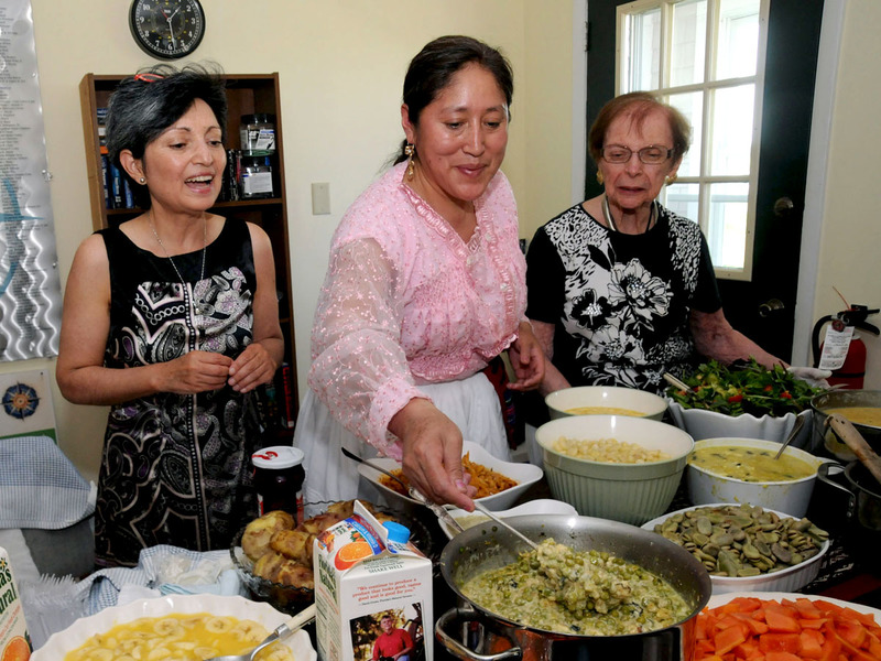 Shown with just one of the tables covered with various food from the Inca culture and ready to serve the guests at the Nethouse are (l-r) Delaware Hispanic Commision's Charito Calvachi-Mateyko, de la Rosa and Mary Brull. de la Rosa is stirring a dish comprised of Inca garlic, oil and peas. BY STEVEN BILLUPS