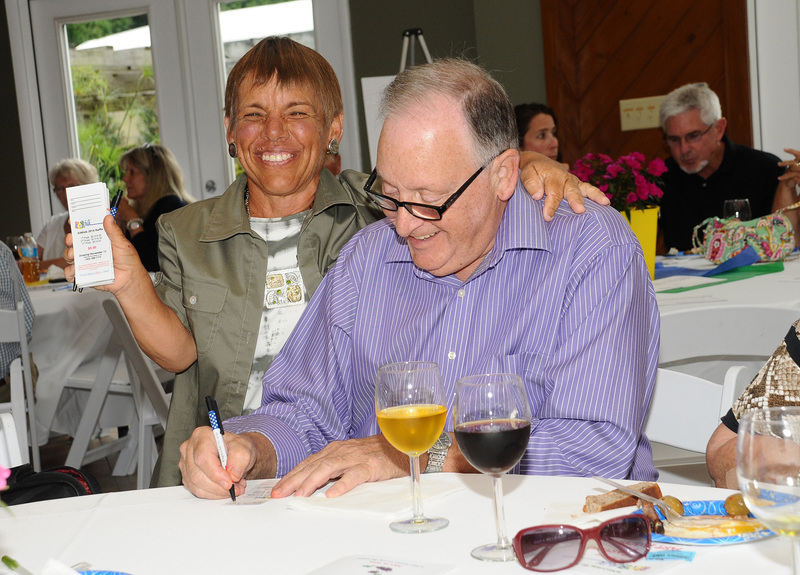 KINfolk volunteer Cheryl Blackman sells a 2014 raffle ticket to Bob Kaplan during the wine tasting at the Cordrey Center. Blackman has raised over $100,000 to help KINfolk purchase laptop computers for children to keep in touch with teachers or family as they are recovering from their illness. BY DAN COOK