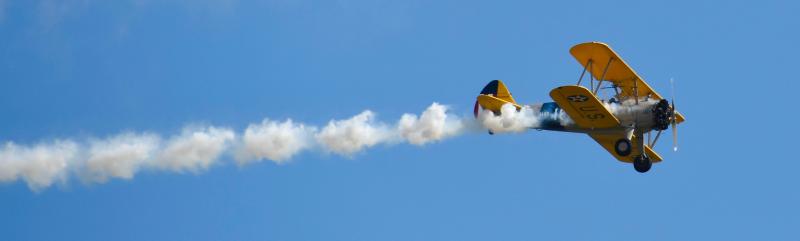 A U.S. Navy Stearman World War II trainer releases smoke as it passes over Delaware Coastal Airport.