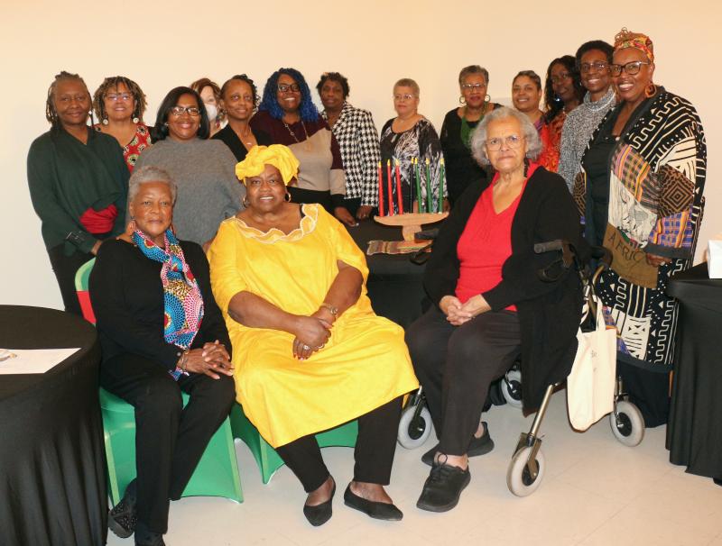 Sunshine Circle Club members surround the kinara. Gathered in back (l-r) are Merry McRae, Doris Person, Tamela Brittingham, Alicia Jones, Antoinette “Mona” Brittingham, Roshi Bull-Turner, Gilda Howard, Jackie Brisco, Gloria Harmon, Stephanie Collick, Christa Edwards, Dana Paskins and Hattie Bull. Waynne Harmon-Paskins, club President Bernice Edwards and Charlotte F. King are in front.