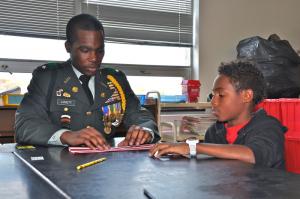 Cape Henlopen JROTC's Sylvester Lovett helps Kevin Williams during the Unit 17 project in Gail Drummond's fifth-grade class. BY RON MACARTHUR