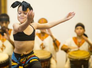 Savayah Brown, 8, the youngest performer in the Sankofa African Dance group keeps the pace with a proud smile. BY DENY HOWETH
