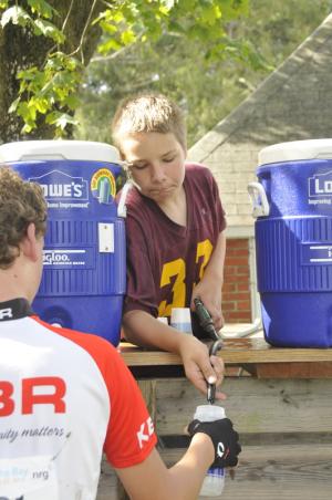 Volunteer Tommy Beenick of Milford fills cyclists' bottles with water and sports drink. BY RON MACARTHUR
