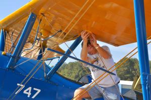 Don Sloan, pilot of this PT-17 Stearman, does some work on a wing after landing at the Sussex County airport. The bi-planes were used for training during World War II; many were sold and converted to crop dusters following the war. BY RON MACARTHUR