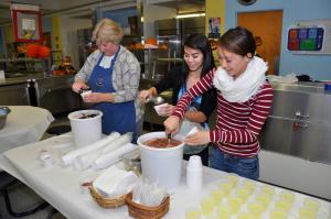 Lyn Buck, left, program assistant, and Savannah and Geri Wallett, Cape High Honor Society volunteers, scoop King's ice cream during the event's reception. BY RON MACARTHUR