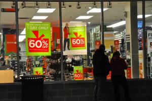 A pair of shoppers waits Thanksgiving night for the doors to open to a store-full of discounts at Tanger Outlets Midway. BY RON MACARTHUR