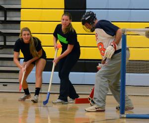 Staff team goalie Dan Cook makes a save on Cape hockey all-state player Allie Yeager of the Crazy Mother Puckers team while staff member Carolyn Sweeney plays defense. BY SHERRI COOK