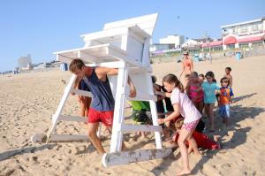 RBP Junior Lifeguard instructor J. P. Williams gets some help carrying a stand into position from the youngest of the participants. BY DAN COOK