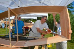 Applying caulk to the Strumsky 1 boat is David Rothman as team members Patrick Dillion, left, and Linda Strumsky hold up the skiff. Not pictured is team member John Dillon. BY RON MACARTHUR