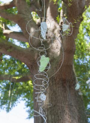 Sea Glass Mobiles by Craig Phillips hang among the trees. BY DENY HOWETH