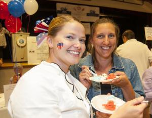 Jen Blakeman of Fish On, left, and Lisa Wheeler of Plate Catering take advantage of down time and try the red, white and blue pistachio ice cream from Hopkins Farm Creamery. BY DENY HOWETH