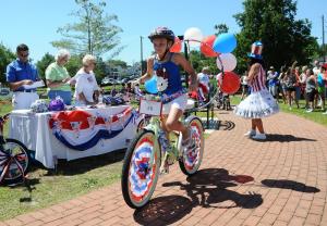 Caroline Griffis, 9, shows off her hand-decorated bike in front of the judges. She took first place in the bike decorating contest and rode home with a new bike donated by Irish Eyes. BY DAN COOK