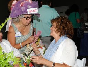 KINfolk volunteer Teresa Fazzalaro sells a 50/50 ticket to Lynda Messick, president of Community Bank. BY DAN COOK