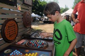 Evan Sydnor plays with a Fox and Goose board game in the Ridge Hollow Game Boards booth. BY STEVEN BILLUPS