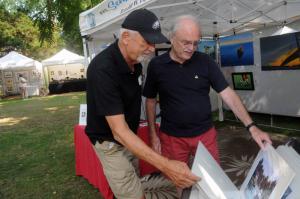 Painter Ron Lightcap, left, of Millsboro shows some of his prints to friend Hollard Franks of Lewes. BY STEVEN BILLUPS