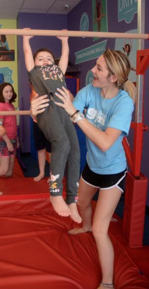 Aurora Palverento, 4, of Georgetown gets help on the bars from instructor Alissa Walton during the open house.