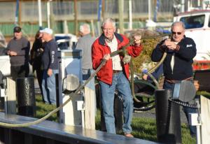 Dave Bernheisel, left, and Bill Battista work together to unhook the line holding the Overfalls in place. NICK ROTH PHOTO