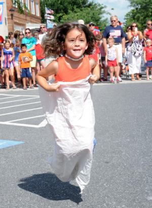 Tessa Moore, 5, gets some air during the sack race. Tessa is visiting her grandmother Marsha Davis in Lewes. BY DAN COOK