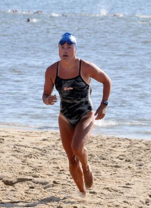 Top female finisher JoAnna Baird of Lutherville Timonium, Md., runs from the ocean to begin the 5K run. She placed first with a time of 30:18. BY DAN COOK