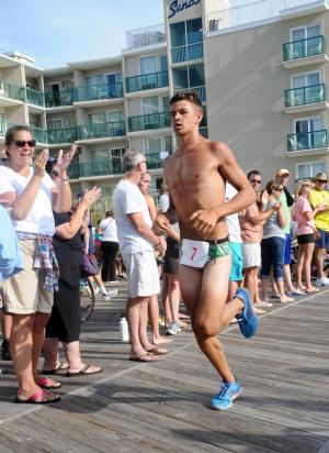Jack Weeks crosses the finish line while his mother, Lauri, applauds with pride. Weeks finished 12th with a time of 31:26. BY DAN COOK
