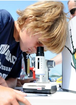 Luke Burton, 9, examines plankton under a microscope from the Sea Grant College Program. BY DAN COOK