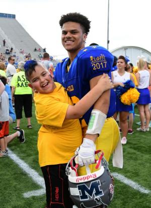 Buddy Joshua Page-Bennett, 10, finds his buddy Elijah Walton of Conrad during the pregame ceremonies. DAN COOK PHOTO