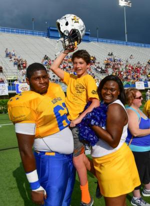 Cape's Robert Mitchell, left, and Mari Horsey hoist their buddy Jayson Kirschner of Lewes during the pregame ceremonies of the DFRC All-Star Football Game. DAN COOK PHOTO