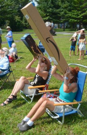 Susan Frey, left, and Nancy Horan of Lewes use their handmade viewing boxes to look at the eclipse at Lewes library.
