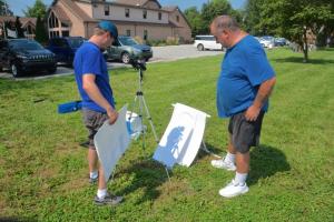 Dave Souva of Millsboro and Guy Souva of Bridgeville view the eclipse using a pair of binoculars aimed at white paper. RON MACARTHUR PHOTO
