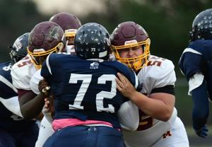 Milford lineman Ritchy Corvil, left, and center Thomas Eisenbrey block out Friends player Robert Baldwin.