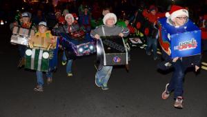 Members of Cub Scout Pack 1 run along the parade route in their homemade “cardboard” derby cars. The scouts won honorable mention.