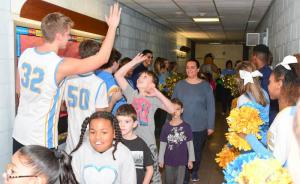 Brody Burton gets a high-five from Cape basketball forward Ian Robertson as they enter the pep rally.