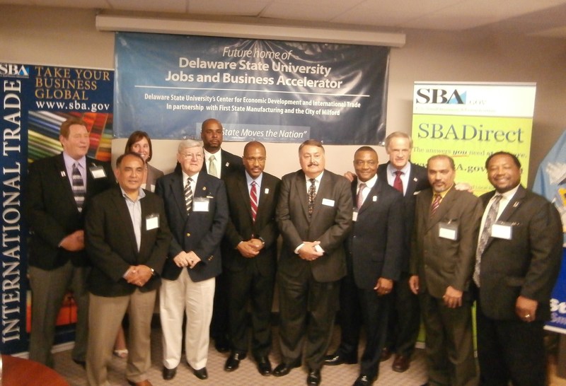 First State Manufacturing owners(l-r) Ashley Wolfe, Eli and Sher Valenzuela join Milford Mayor Ronnie Rogers, Dr. Michael Casson, Delaware State University President Dr. Harry Williams, SBA Director Tony Leta, Dr. Shelton Rhodes, U.S. Sen. Tom Carper, Dr. Nanda Viswanathan and Dr. Alton Thompson as they gather to formalize their business agreement. BY MOLLY MACMILLAN