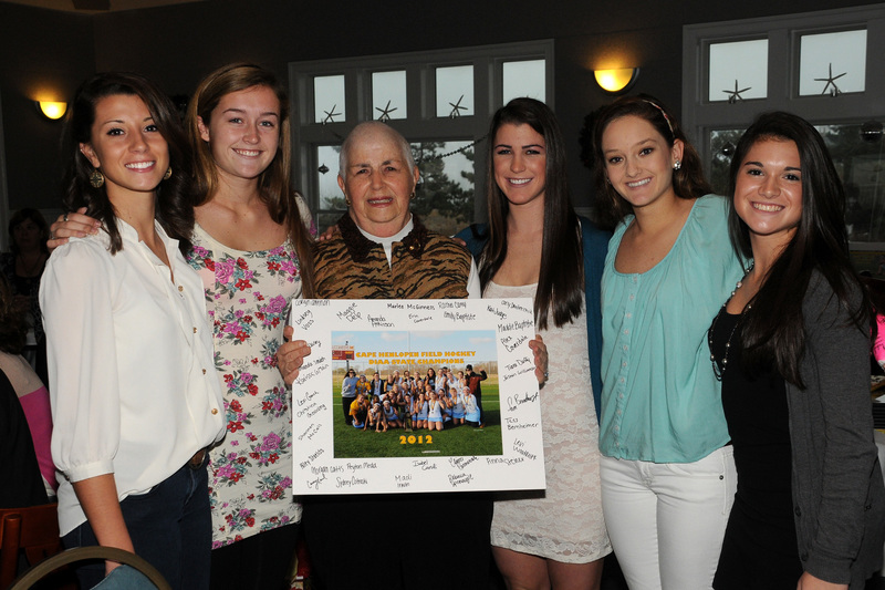 Cape seniors (l-r) Izzie Delario, Anna Frederick, Sara Young, Emily Baptiste and Alex Coverdale present Barbara Dougherty, center, with an autographed team picture. "Cookie" delivered some inspirational hockey history to the team late in the season before undergoing serious cancer surgery. BY DAN COOK