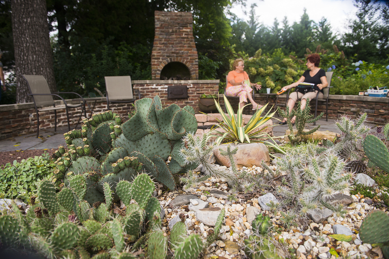 Barbara Sherrer and Donna Brown relax at the Pepper's outdoor barbecue pit. Cactus and succulents are displayed in the rock garden. BY DENY HOWETH