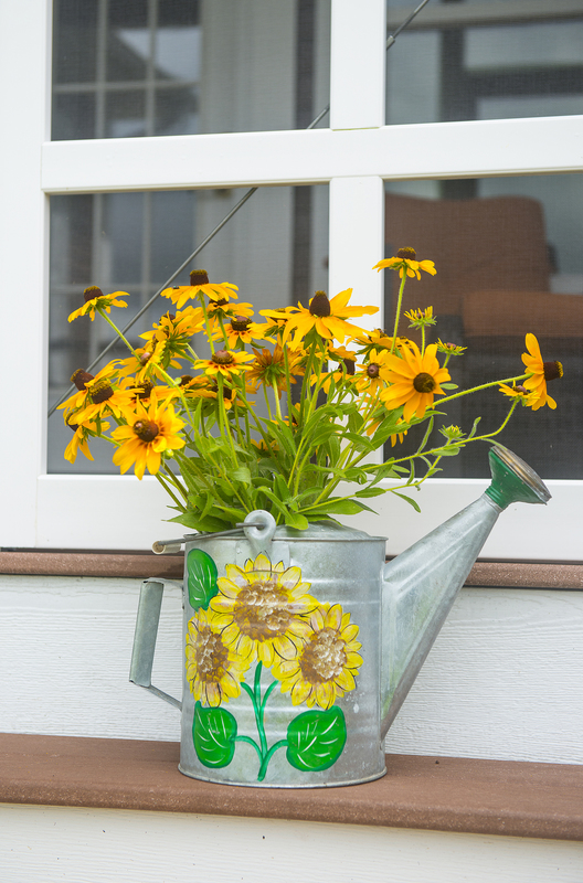 Daisies in a rustic watering can adorn the home of Nancy and Dick Trask in Heritage Creek BY DENY HOWETH