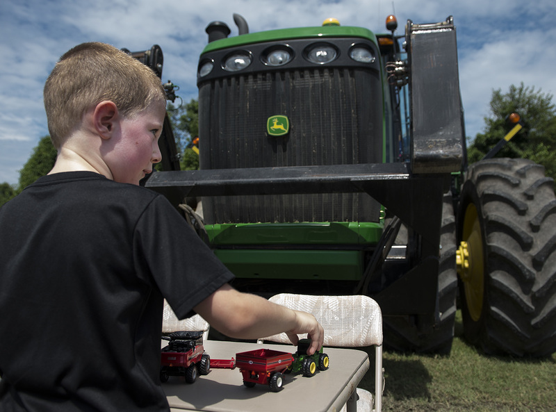Dale Edwards, 5, is more intrigued by the small tractor toys than the large one that looms in front of him. BY DENY HOWETH