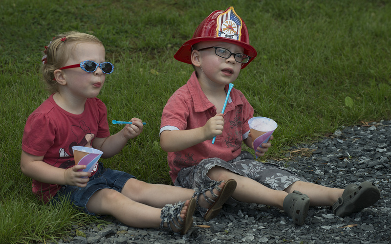 Two-year-old twins Claire and Joel Denham relax with a snow cone after a ride on the Milton Clipper Express. BY DENY HOWETH