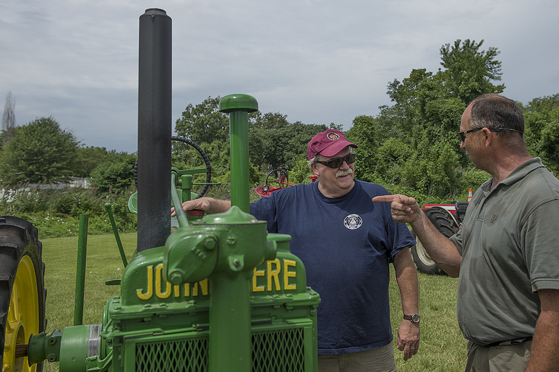 Denny Hughes, left, and Skip Betts chat about the hand crank starter, 1938 John Deere tractor. BY DENY HOWETH