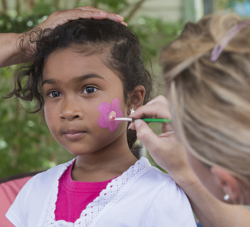 Shaila Mirwani, 7 holds as still as a statue while she receives a posey painting on her cheek. BY DENY HOWETH