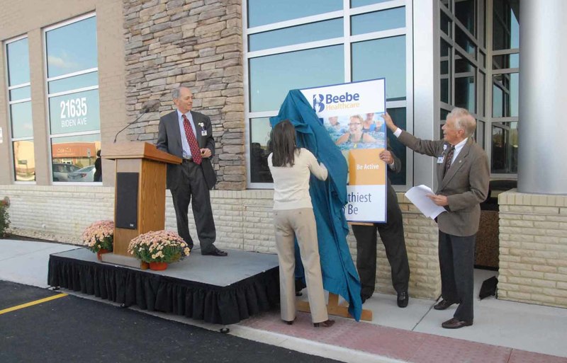 Beebe Medical Center announced its new name, Beebe Healthcare, Oct. 29 at Beebe’s new outpatient services facility in the College Park Medical Pavilion in Georgetown. With a large crowd looking on, the new name is revealed by Mary Green, Beebe marketing and communications coordinator, as Beebe Healthcare President and CEO Jeff Fried, left, and Chairman of the Board of Directors the Hon. William Lee look on. BY STEVEN BILLUPS PHOTOS