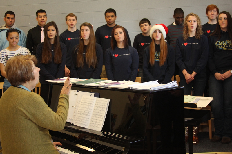 Cape chorale director Louise Foster directs her group through a holiday song. Pictured singing in the back row are (l-r) Austin Brooks, Joel Torres, Andy Maglione, Marcus Davis, Zane Daddoya, Jeremiah Sturges and Ben Wiswell. In front are Mariko Daisey, Ashley Avelleyra, Kaitlin Philcox, Nora Carle and Morgan Vezmar. BY MELISSA STEELE