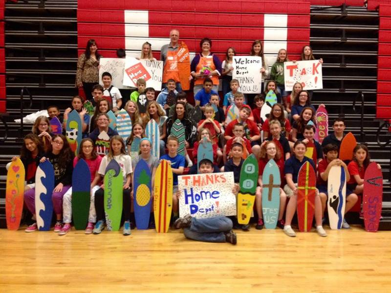 Eagle's Nest students hold up thank-you posters to Home Depot as they show off their custom longboards. Eagle's Nest art teacher Robin Stanton is at top left. Home Depot representatives Frank Manning and Karen Lewis are at top center. SOURCE SUBMITTED